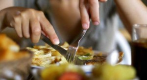 A person eating food with spoon and fork